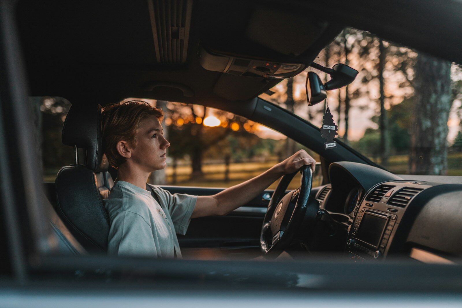 a man sitting in a car with his hand on the steering wheel